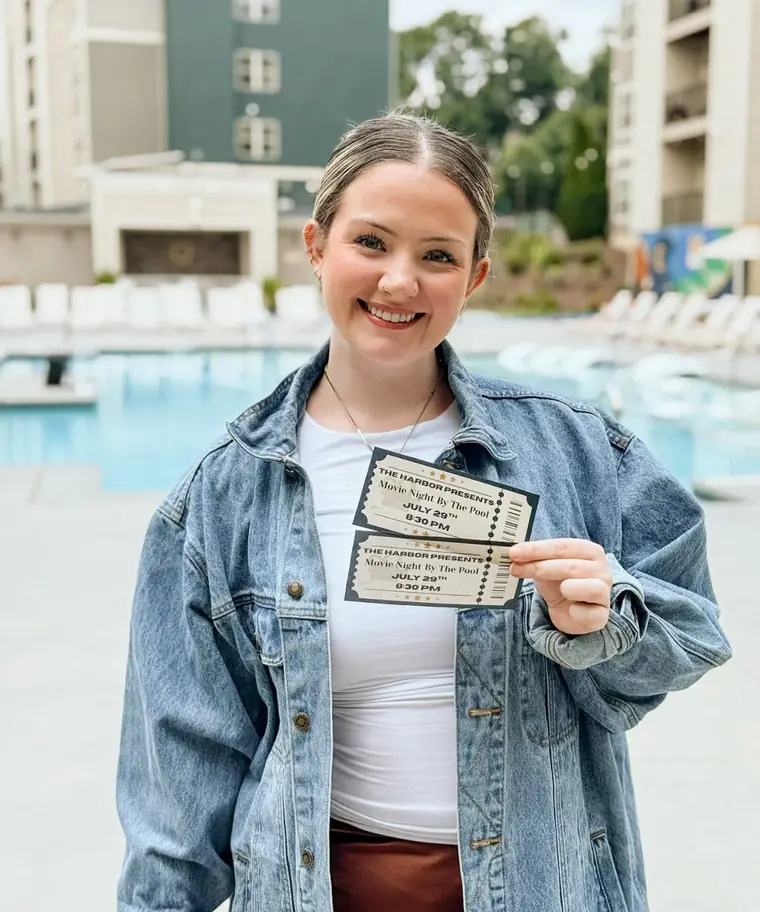 A resident by the pool with tickets to movie night at The Harbor